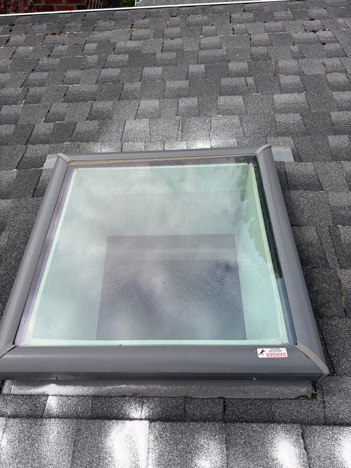 Skylight on a Capitol Hill roof after moss removal, with the white moss-prevention treatment laid in a band on the shingles below the curb